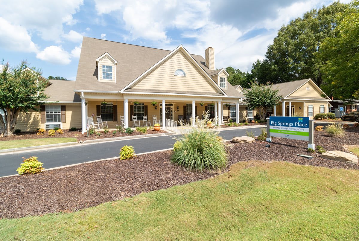 A large house with a well-maintained yard under a partly cloudy sky.
