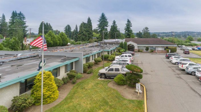 Aerial view of a motel with a parking lot surrounded by trees.