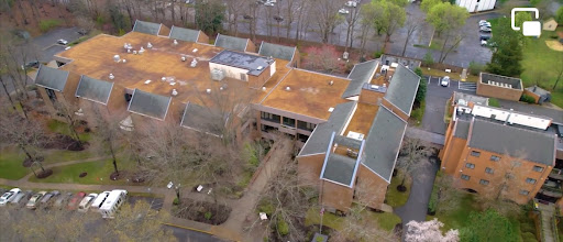 An aerial view of a complex featuring multiple buildings surrounded by trees.