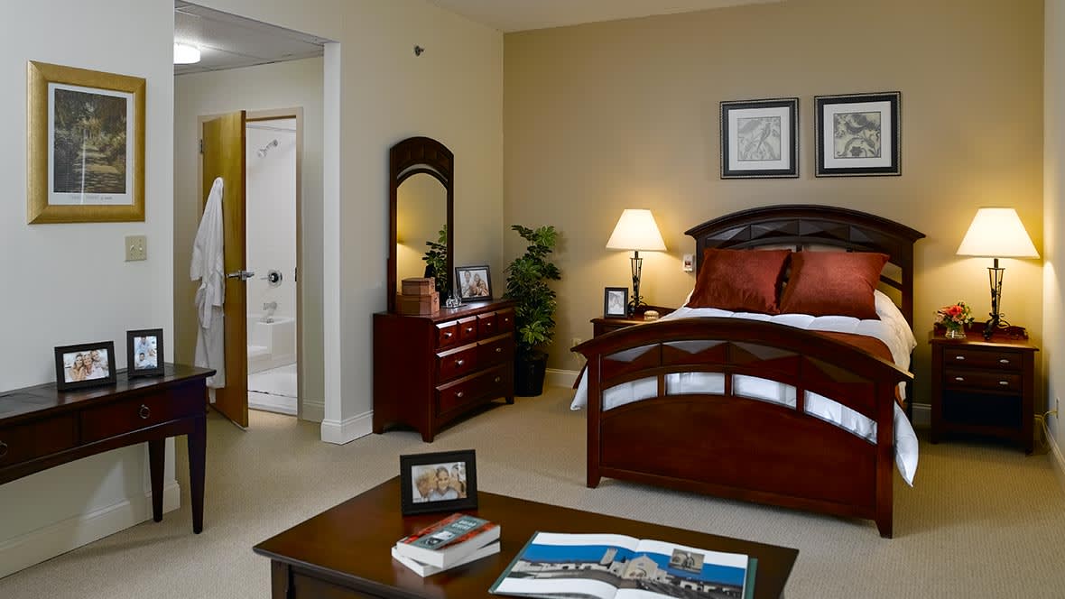 A cozy and well-decorated bedroom featuring a large bed, dresser with mirror, and warm lighting.