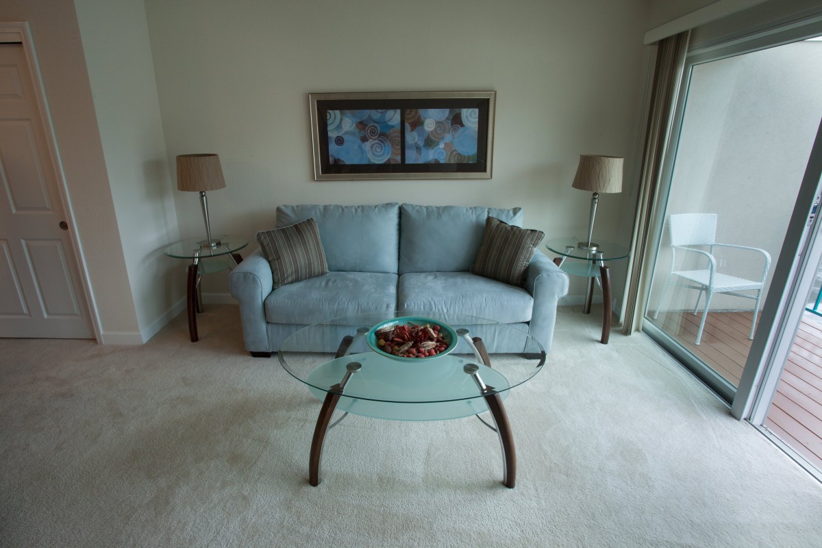 A cozy living room with a blue sofa, glass coffee table, and elegant decor.