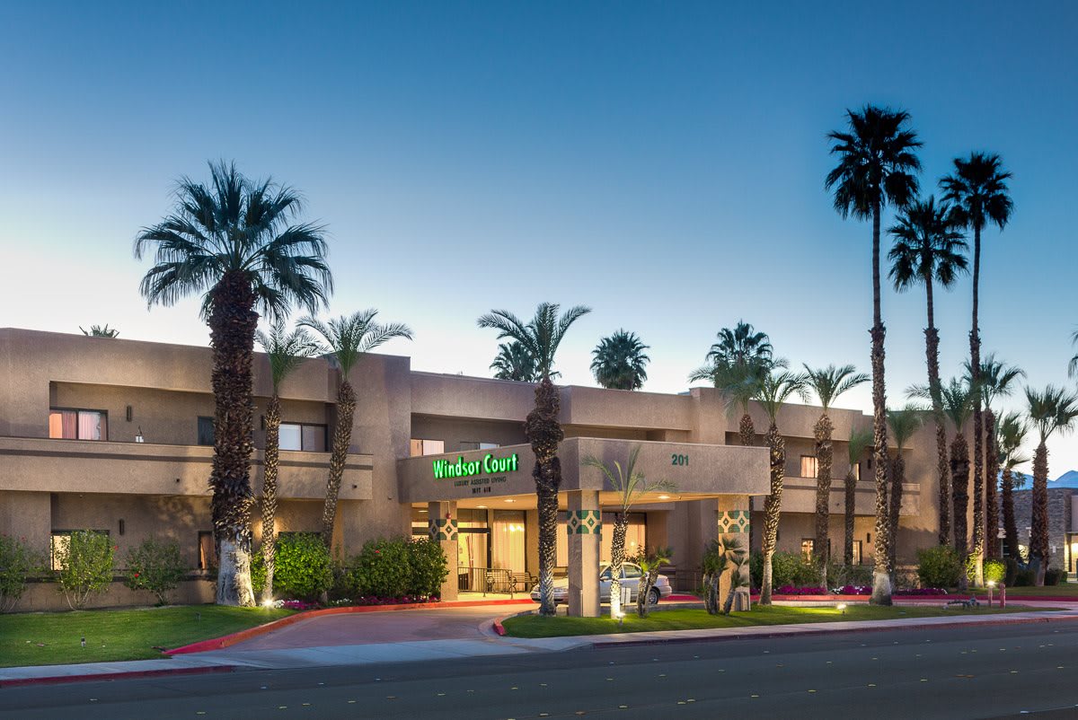 A hotel building with palm trees in the evening light.