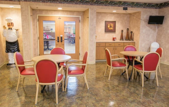A cozy indoor dining area with red cushioned chairs and round tables.