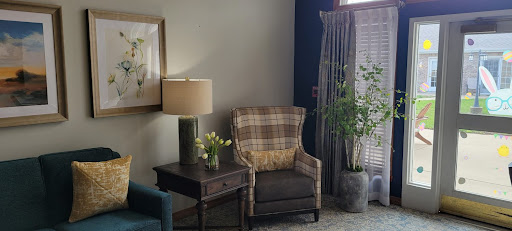 A cozy corner of a living room featuring a comfortable armchair, lamp, and decorative elements.