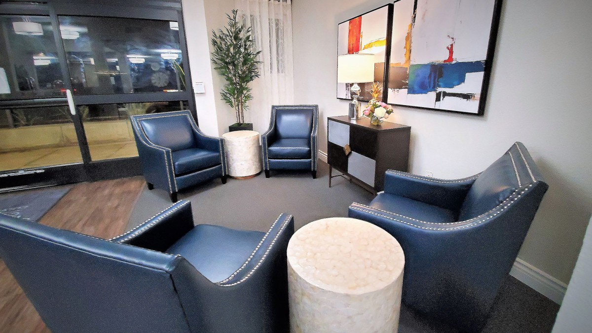A modern waiting room with blue leather chairs and contemporary artwork.