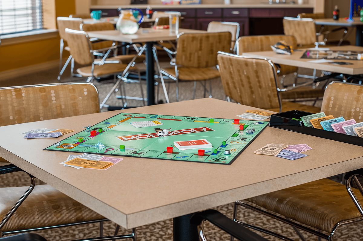 A table in a cafe setting with a Monopoly board game set up for play.