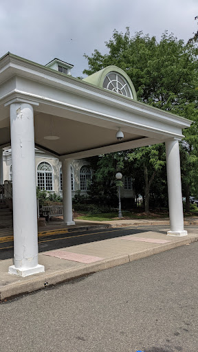 A view of a building entrance featuring elegant white columns and a canopy.