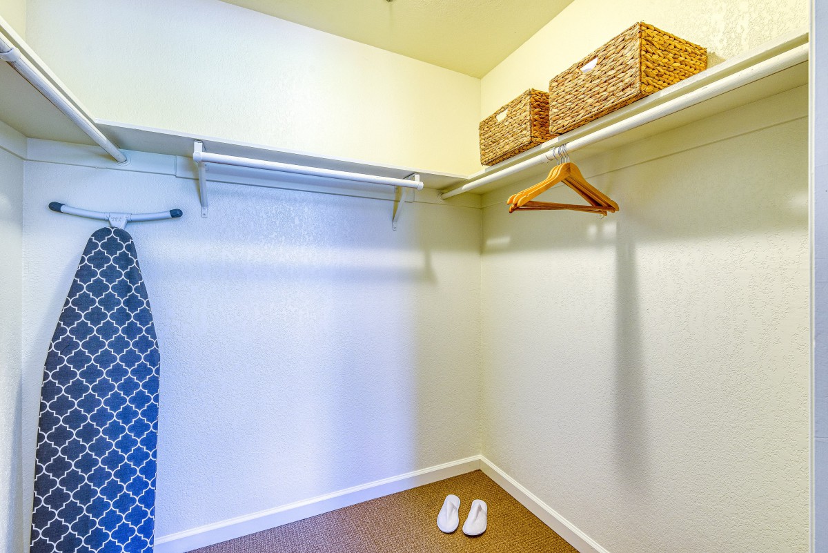 A minimalistic, empty closet with a few wooden hangers and storage baskets.