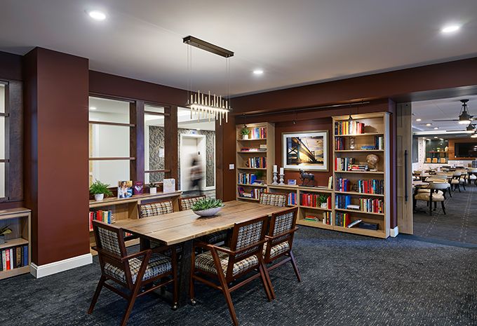 A cozy library room with a table, chairs, and bookshelves.