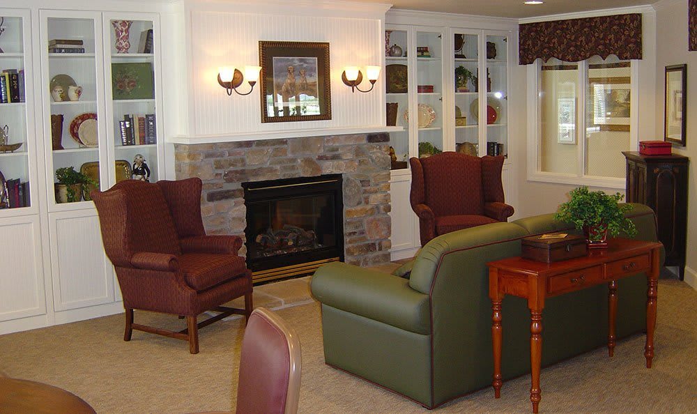A cozy living room with a fireplace, armchairs, and bookshelves.