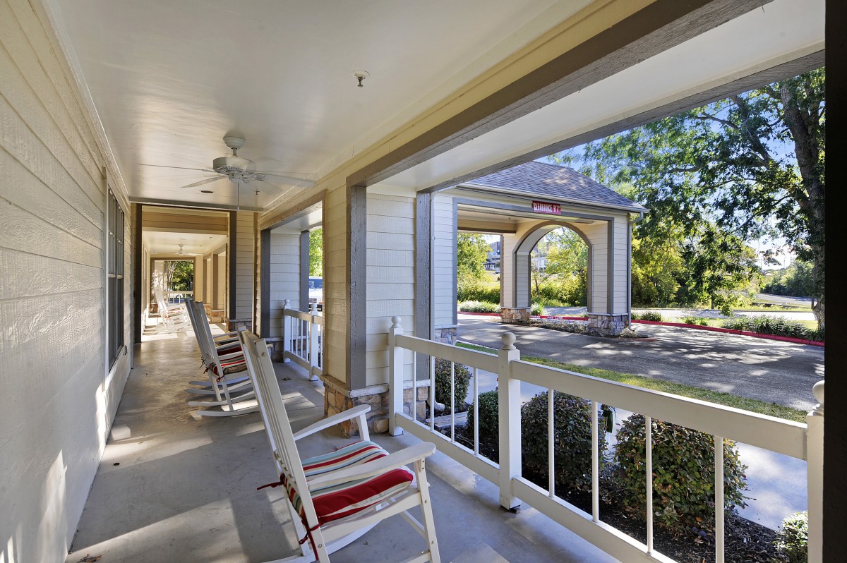 A spacious porch with rocking chairs overlooking a peaceful outdoor setting.