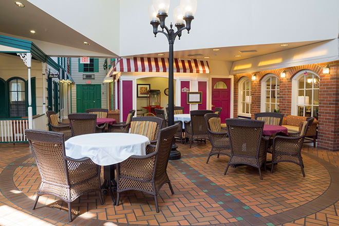 A cozy indoor cafe setting with tables and chairs arranged on a brick floor, illuminated by a vintage-style street lamp.