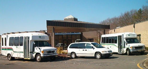 A parking lot with several vans in front of a building on a clear day.
