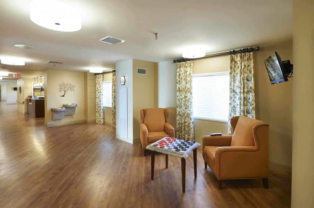 A cozy sitting area featuring two armchairs, a small table with a board game, and patterned curtains.