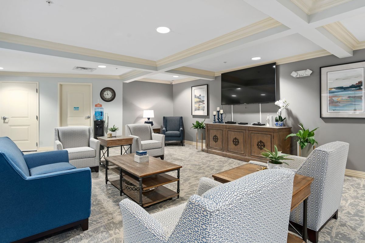 A modern waiting room with comfortable seating and a large TV.