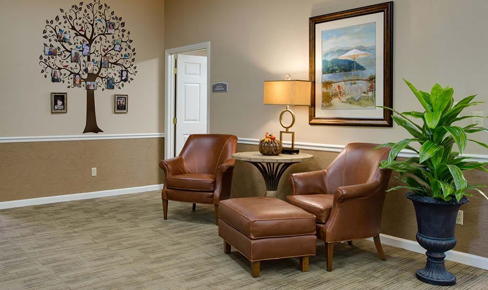 A cozy living room with leather chairs and a table, adorned with a lamp and wall art.