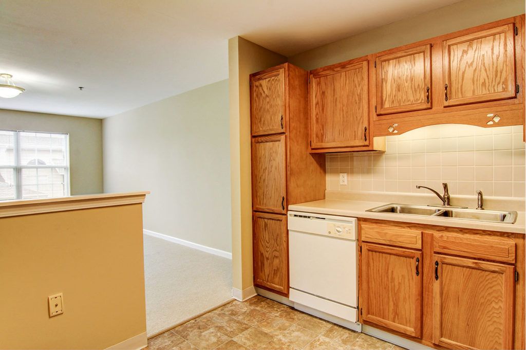 A compact kitchen with wooden cabinets, a built-in dishwasher, and a sink.