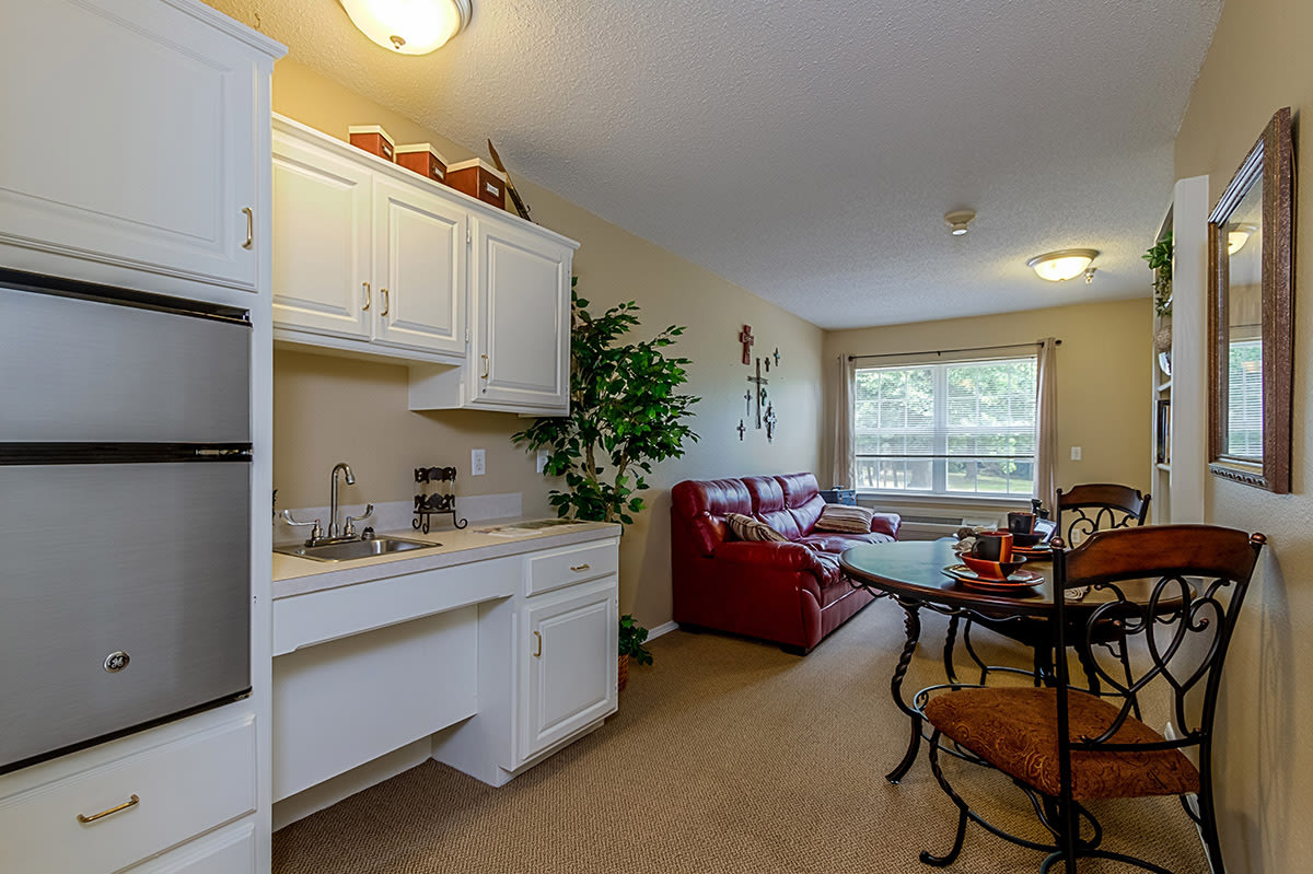 A cozy apartment interior with a kitchen area and a well-lit living room featuring comfortable furniture.
