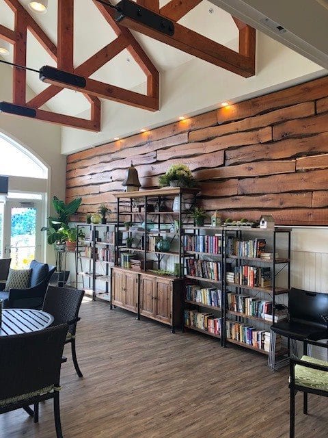A cozy interior space featuring bookshelves with various books and decorations, highlighted by a decorative wood-paneled wall and ceiling beams.
