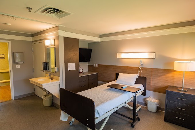 A modern hospital room with a single bed and amenities.
