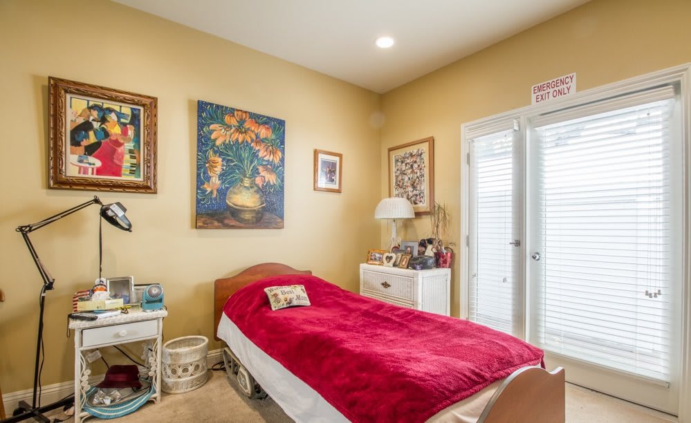 A cozy bedroom with a single bed and vibrant artwork on the walls.