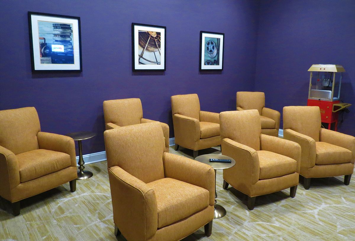 A cozy waiting area with comfortable chairs and artwork on a purple wall.