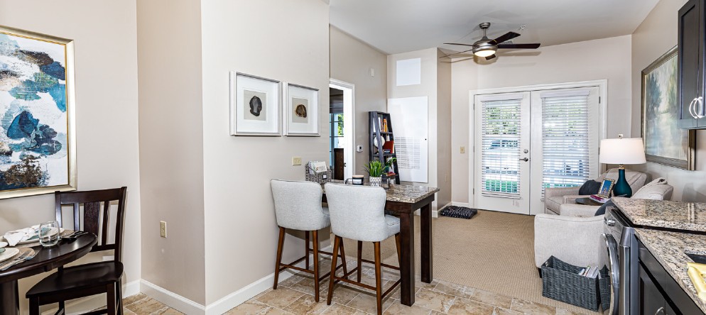 A modern dining area featuring a wooden table with bar stools, wall art, and stylish home decor in an open space.
