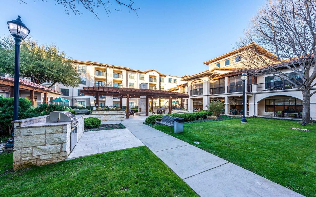 A modern residential building with a landscaped courtyard and walking paths.