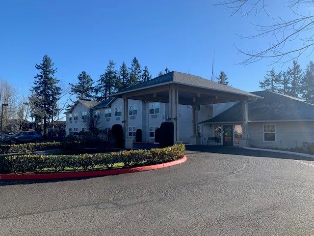 A fire station with a driveway on a sunny day, surrounded by trees.