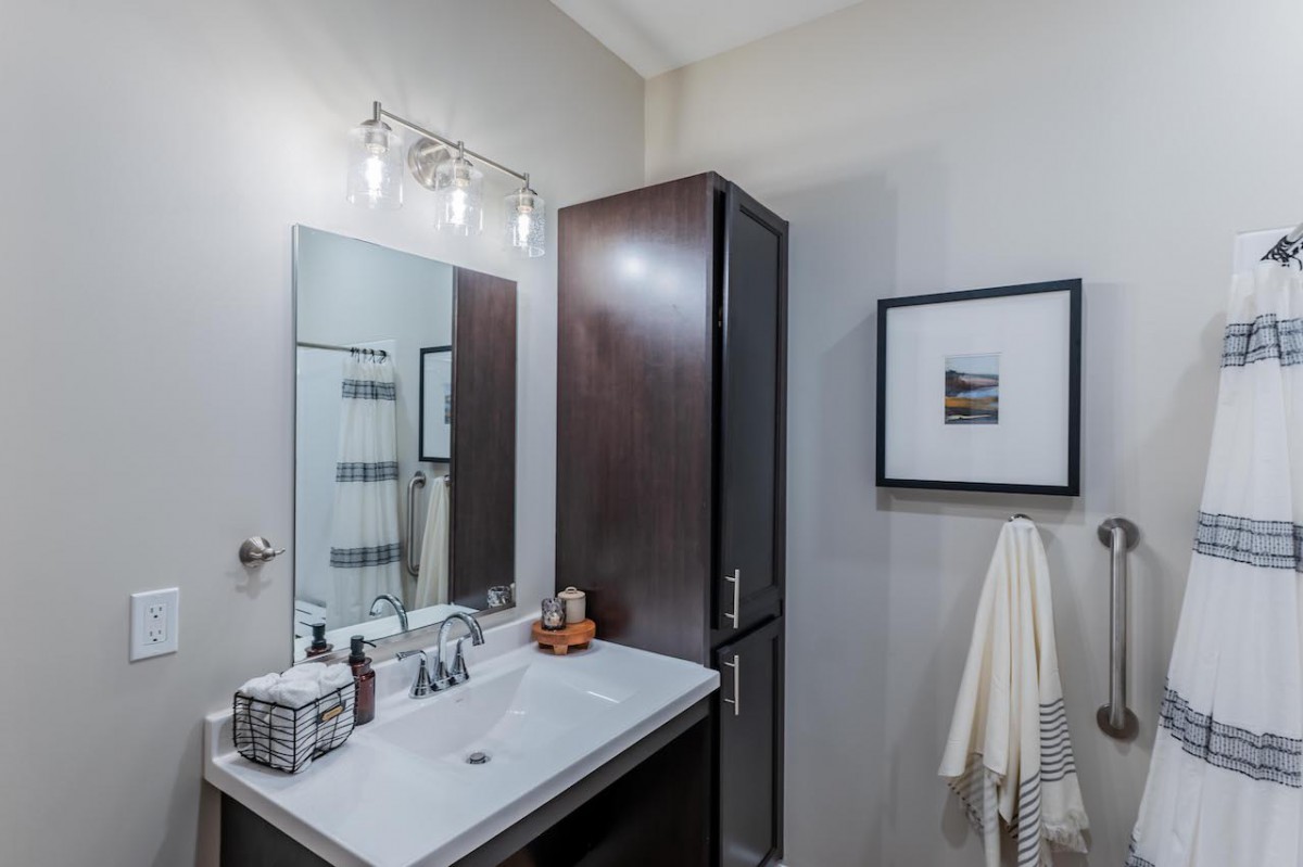 A modern bathroom featuring a sleek sink, mirror, and dark wood cabinet.