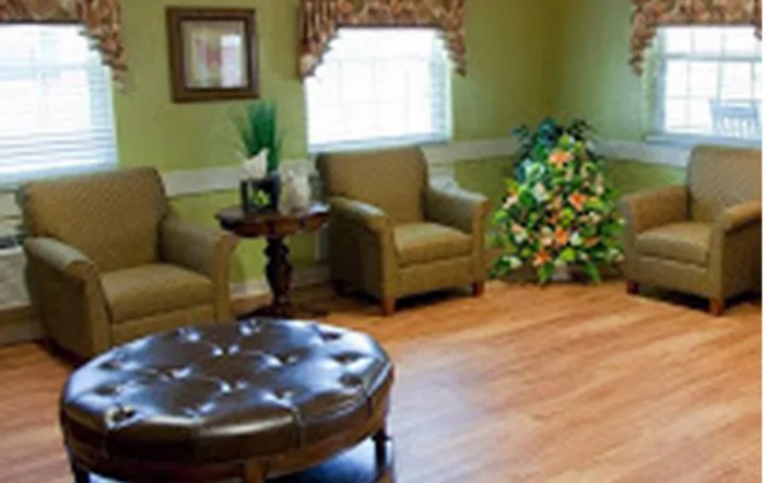 A cozy living room with comfortable chairs, a small round table, and decorative plants.