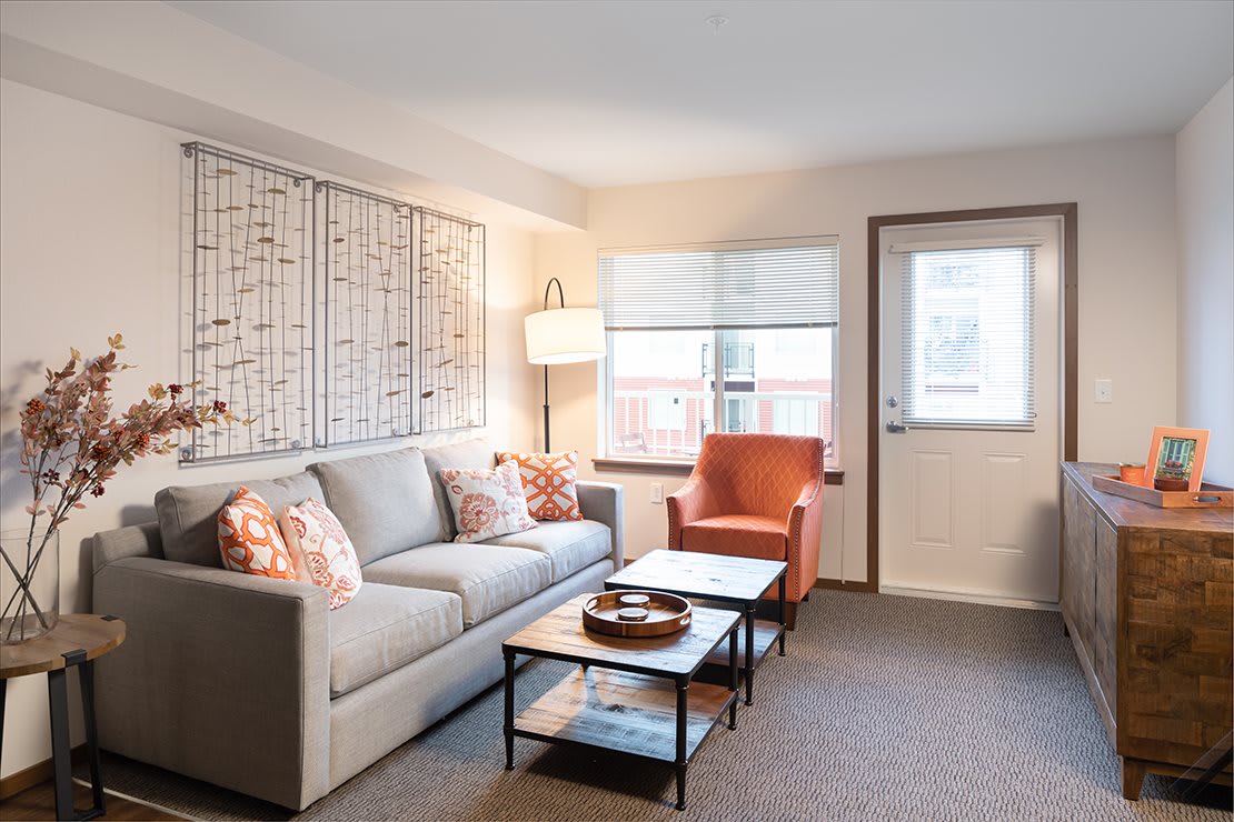 A cozy living room with a grey sofa, orange armchair, and modern decor.