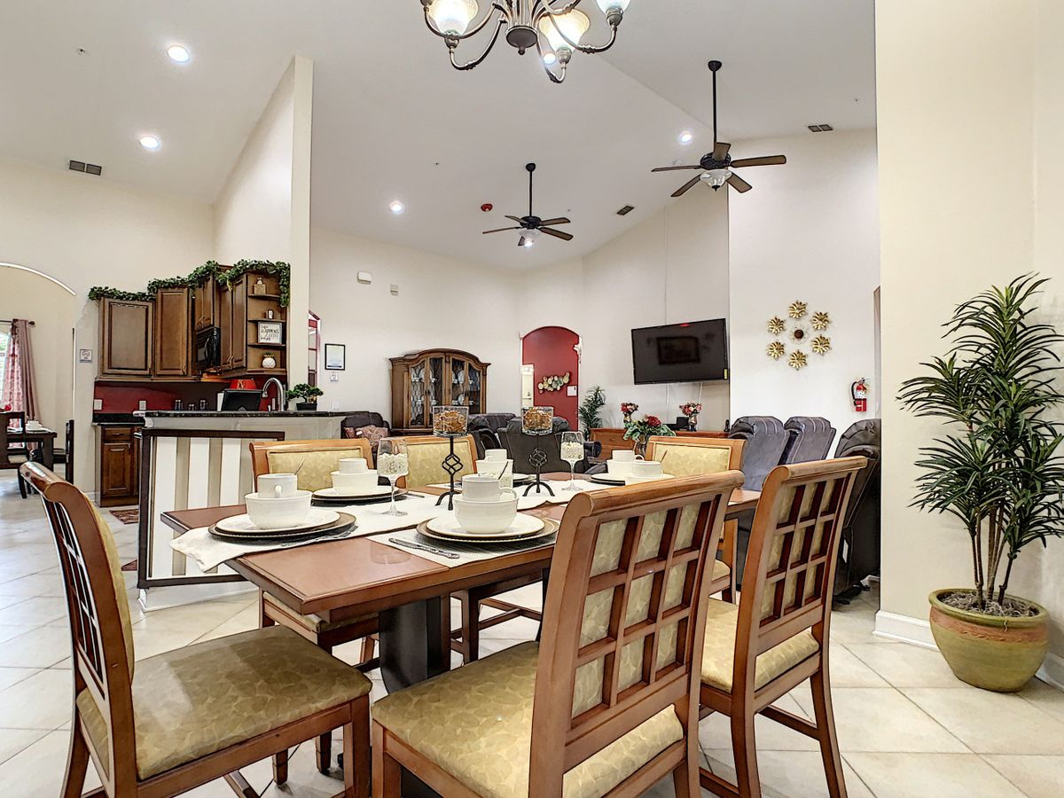 A modern and spacious dining room with a well-set table, adjacent to an open kitchen area.