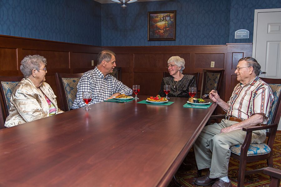 Four seniors enjoying a meal together in a restaurant setting.