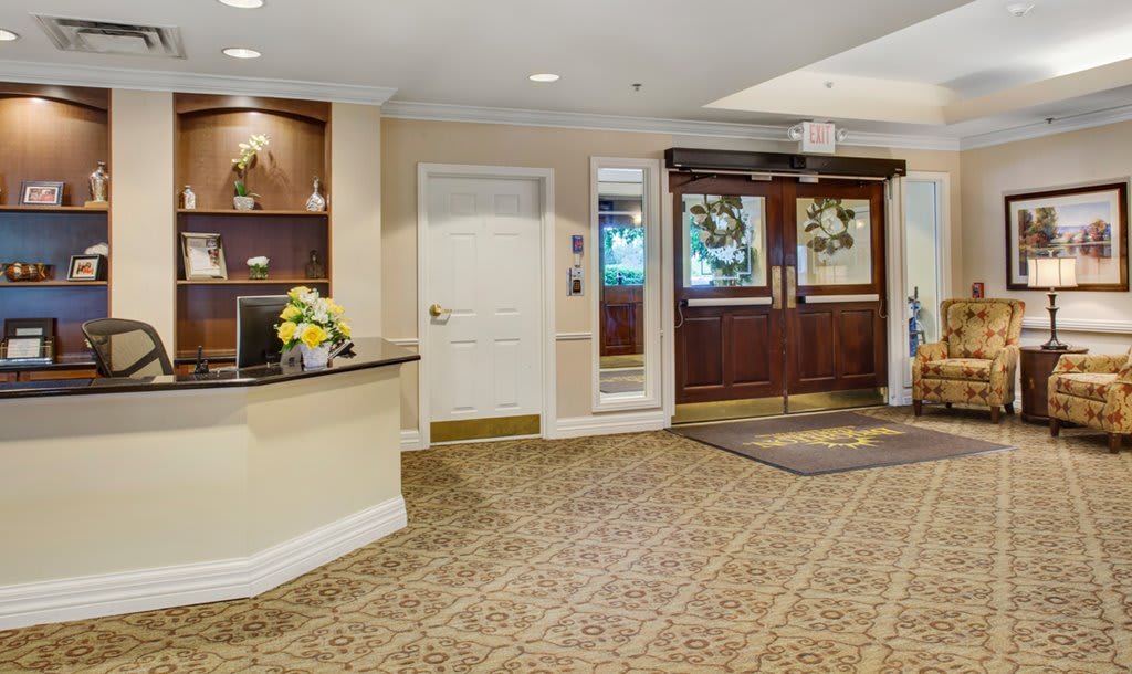 A hotel lobby with a reception area and entrance doors.