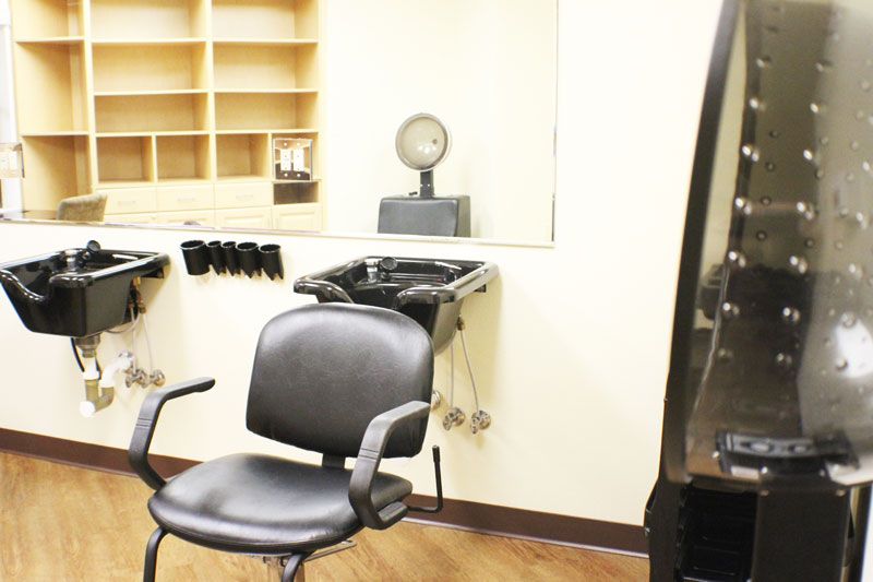 An interior view of an empty hair salon station with a chair and washing sink.