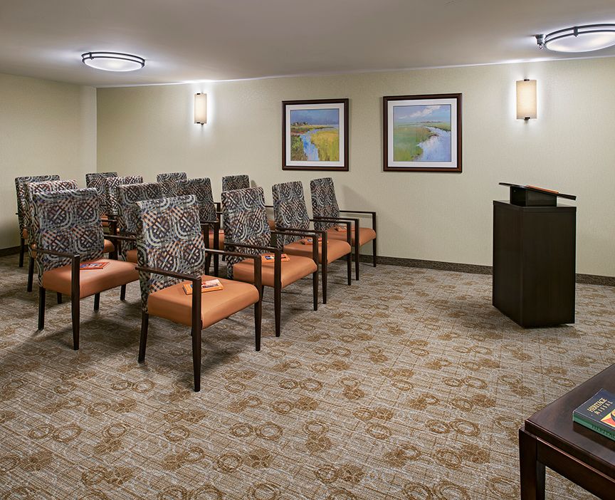 A small conference room with neatly arranged chairs facing a podium.