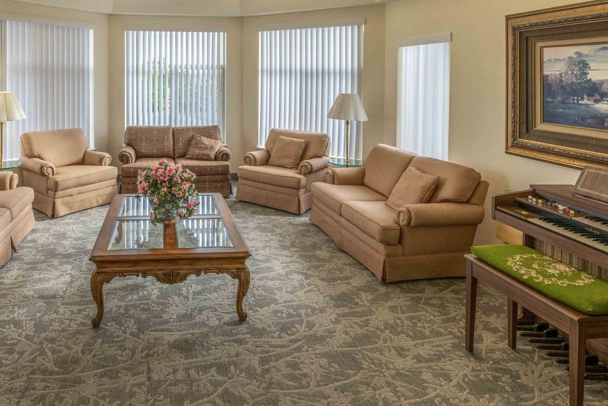 A well-furnished living room with multiple sofas and a coffee table, decorated with flowers.