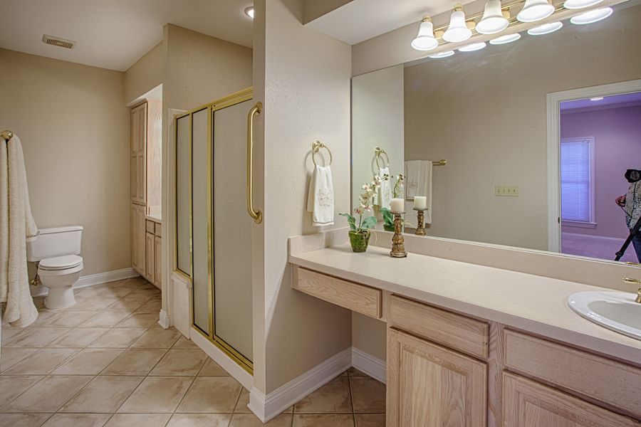 A spacious bathroom featuring a large vanity with mirror, a walk-in shower, and tiled flooring.