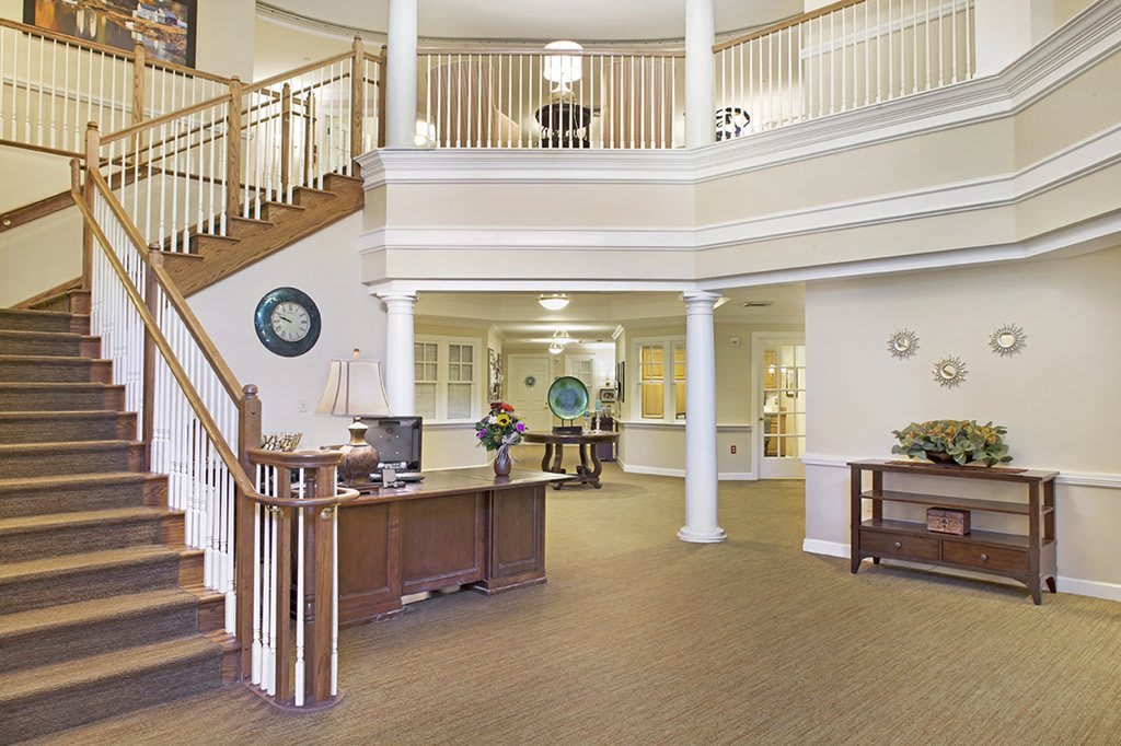 A spacious and welcoming lobby with a central staircase, elegant columns, and balcony.