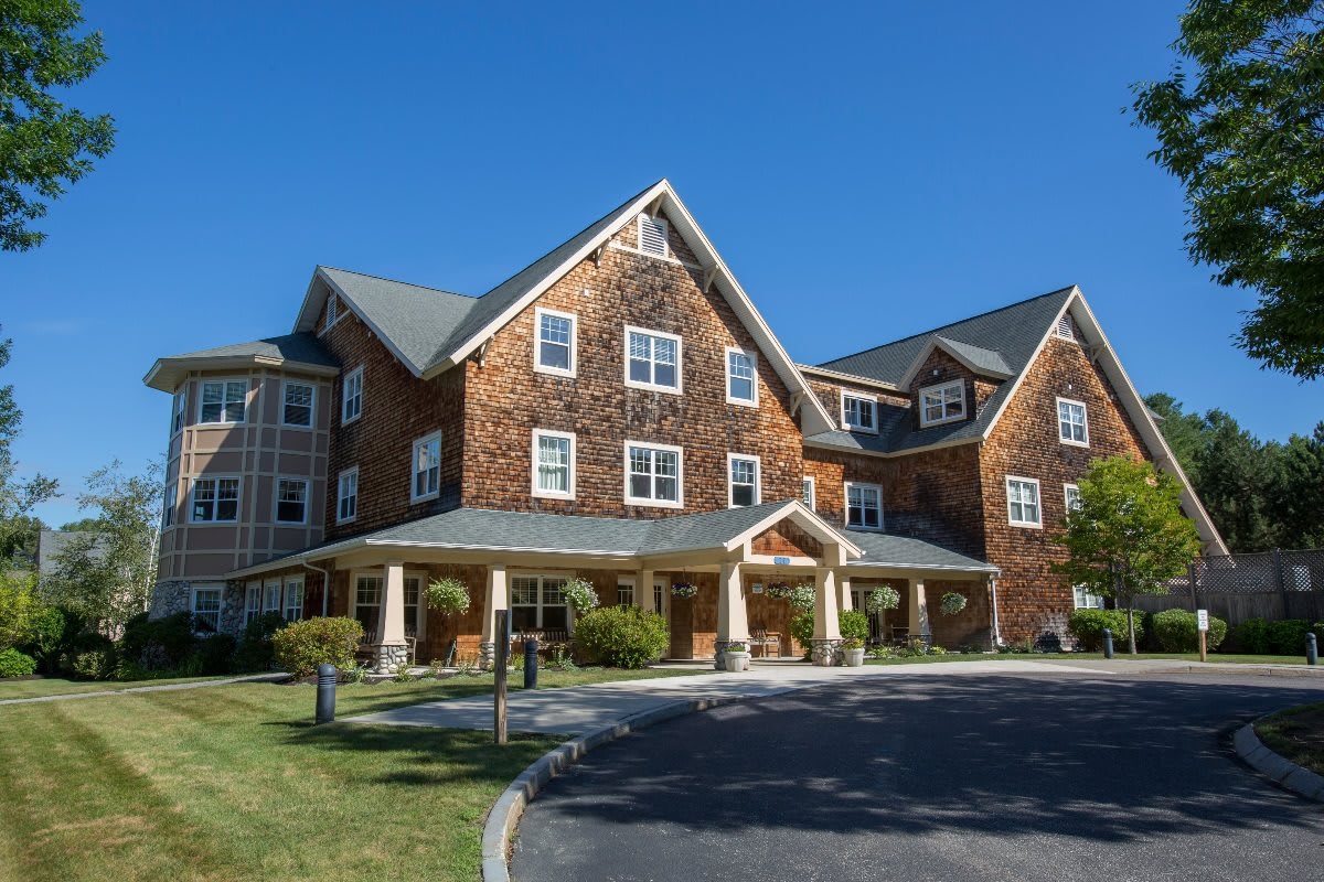A modern residential building with a gabled roof and stone facade under a clear blue sky.