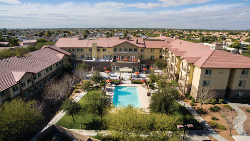 Aerial view of a resort-style apartment complex featuring a central swimming pool and landscaped gardens.