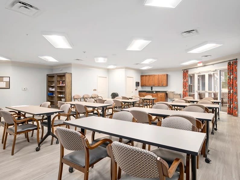 An empty classroom with arranged tables and chairs under bright lighting.