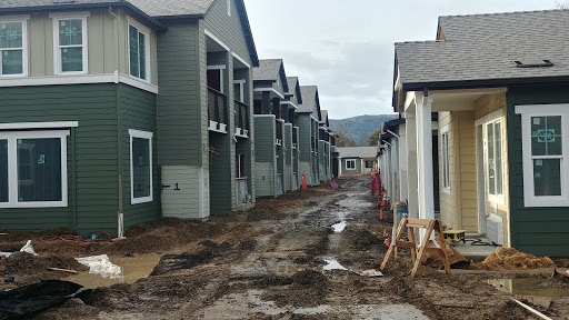 A view of a residential construction site with multiple units and muddy pathways.