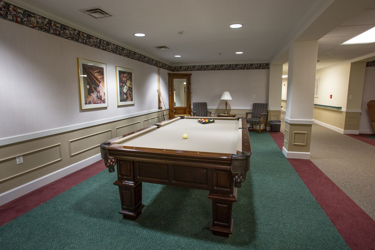 A billiard room featuring a pool table, green carpet, wall artwork, and overhead lighting.