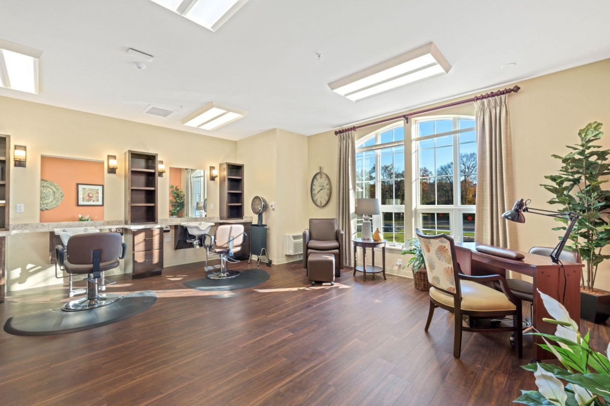 A spacious and well-lit hair salon interior with comfortable seating and large windows.