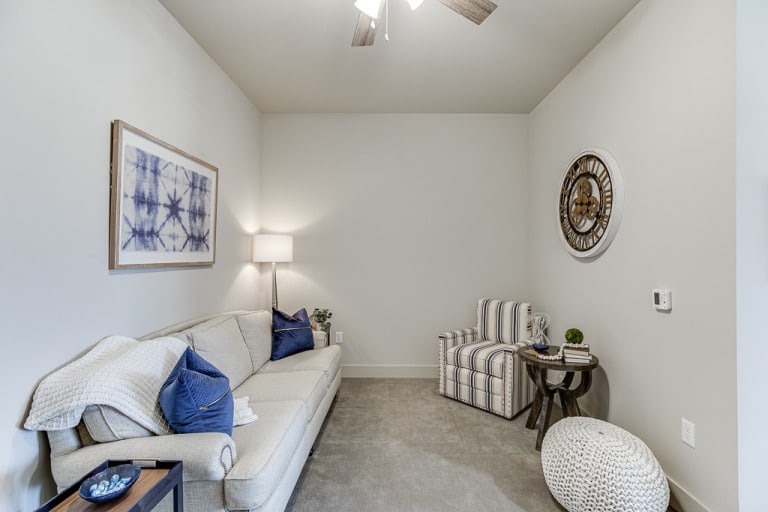 A cozy living room with a sofa, striped chair, and wall decor.