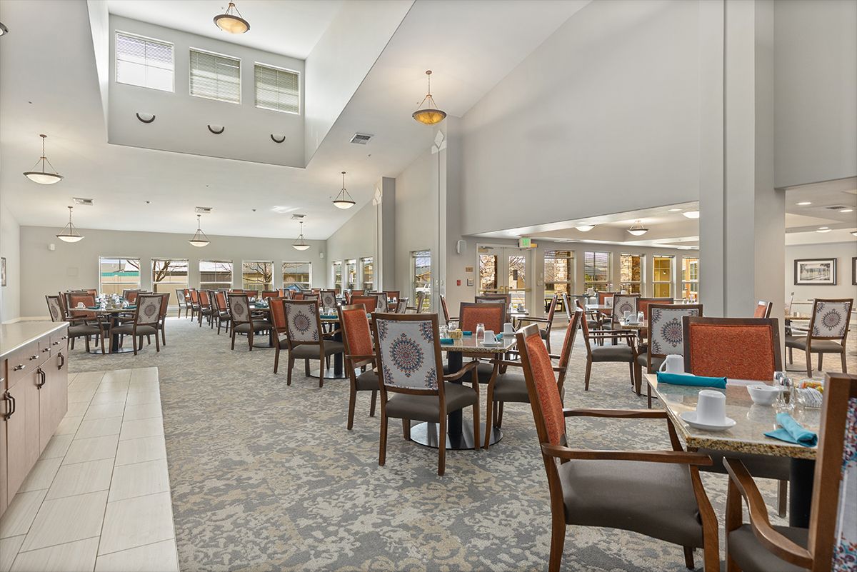 A spacious dining area with neatly arranged tables and chairs, illuminated by elegant chandeliers.