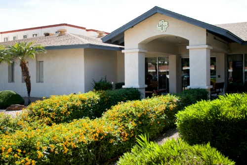 A welcoming entrance to a well-maintained building surrounded by lush greenery.