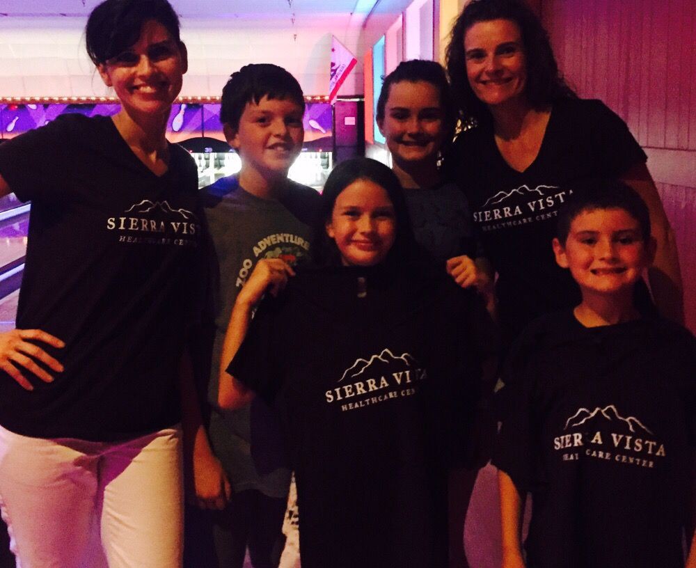 A group of people smiling indoors, wearing matching t-shirts.